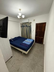a bedroom with a blue bed and a television at Apartamento Angélica in Resistencia