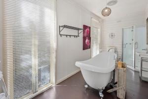 a bathroom with a white tub and a sink at Courtyard Cottage Healesville, close to everything in Healesville +24 photos