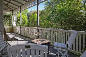 a porch with chairs and a table and an umbrella at Courtyard Cottage Healesville, close to everything in Healesville