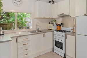 a kitchen with white cabinets and a sink and a stove at Courtyard Cottage Healesville, close to everything in Healesville