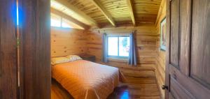 a small bedroom in a log cabin with a bed at Cabaña Paty in Mazamitla