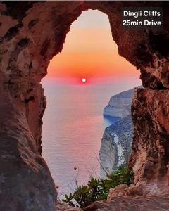 a view of the sunset through a rock formation at Country View Retreat in Żabbar