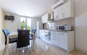 a kitchen with white cabinets and a table and chairs at Apartments Dalis in Milna