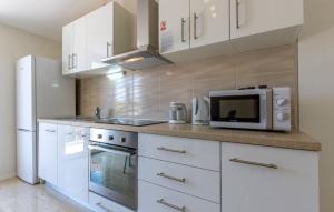 a kitchen with white cabinets and a microwave at Apartments Dalis in Milna