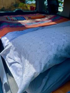 un letto con una trapunta bianca sopra di Go Camp Maui-Exploring Maui in a Campervan a Ah Fong Village