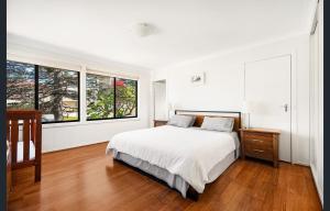 a white bedroom with a bed and two windows at Spacious King Bed Three Bedroom Home 5 Minutes Walk To Three Sisters in Katoomba