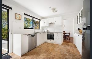 a kitchen with white cabinets and a large window at Spacious King Bed Three Bedroom Home 5 Minutes Walk To Three Sisters in Katoomba