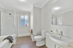 a white bathroom with a toilet and a sink at Spacious place to live in the dream of Schofields in Riverstone +26 photos