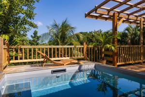 a swimming pool with a wooden fence and a pergola at Kaz 'Bwadend in Le Vauclin