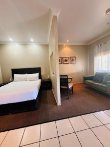Un dormitorio con una cama, un sofá y una mesa. en Best Western Bungil Creek Motel, en Roma