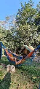 una mujer tumbada en una hamaca junto a un perro en Eco Camping do Véu, en Majé