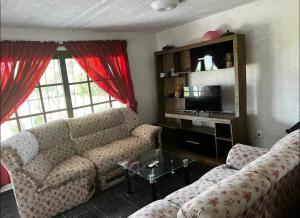 a living room with a couch and a tv at CASA PARA 10 PERSONAs in Aguas Dulces