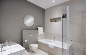 a bathroom with a sink and a toilet and a shower at The Capital on Bath in Johannesburg