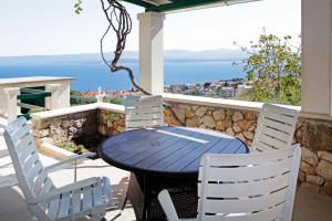 a table and chairs on a patio with a view of the ocean at Family friendly house with a swimming pool Bol, Brac - 23787 in Bol +8 photos
