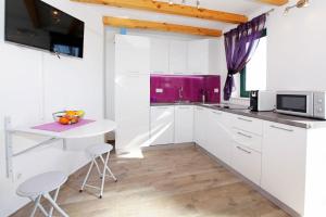 a kitchen with white cabinets and a table and a microwave at Family friendly house with a swimming pool Bol, Brac - 23787 in Bol