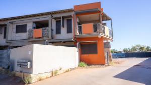 南黑德兰Suburban Sanctuary South Hedland的橙色和白色的公寓楼,设有围栏