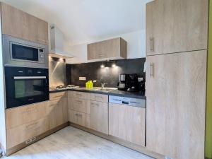 a kitchen with wooden cabinets and a sink and a microwave at Charmante maison rénovée avec 3 chambres, garage, et animaux admis à Gerbamont - FR-1-589-161 in Gerbamont 