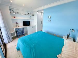 - une chambre bleue avec un lit et un bureau dans l'établissement Apartamento de frente para o Mar, à Guarapari