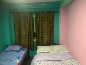 a bedroom with two beds and a window with curtains at Swoyambhu Home Stay in Kathmandu +1 photo