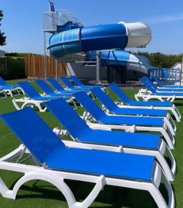 a row of blue lounge chairs in front of a water park at Joli mobilhome 7 places, 3 chambres Blois Amboise Piscine in Onzain