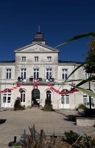 a large white building with a red ribbon in front at Au Coin Maison in Ruffec