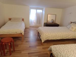 a bedroom with two beds and a window and wooden floors at Au Coin Maison in Ruffec