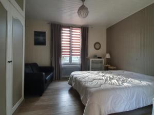 a bedroom with a bed and a couch and a window at Maison Vendéenne Rénovée, Proche Plage et Commerces, Chambres Indépendantes, Jardin Privé - FR-1-476-76 in La Faute-sur-Mer