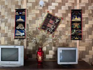 a table with two monitors and a vase with flowers at Minh Ngoc Homestay Dien Biên Phu in Ban Hin Lom
