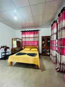 a bedroom with a yellow bed and red curtains at Lavender Apartment Welimada in Ambagasdowa