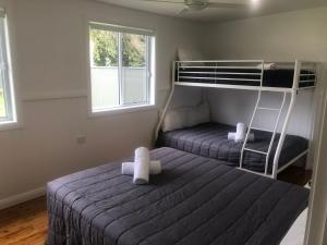 a bedroom with a bed and a bunk bed at Googley's Cottage in Dunbogan