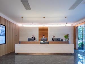 two people sitting at a reception desk in a lobby at Atour Hotel Shenzhen Nanshan West Lizhi Valley Industrial Park in Shenzhen