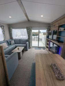 a living room with a blue couch and a table at Bright, modern & stylish deluxe caravan located on the very popular Swanage bay view holiday park in Swanage