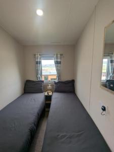 two beds in a small room with two windows at Bright, modern & stylish deluxe caravan located on the very popular Swanage bay view holiday park in Swanage +8 photos