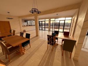 a dining room with a wooden table and chairs at Fyndy Hotel Bir Gandouz in Aousserd