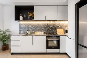 a kitchen with white cabinets and a stove at Brand New 2BR Apt at Mel CBD in Melbourne