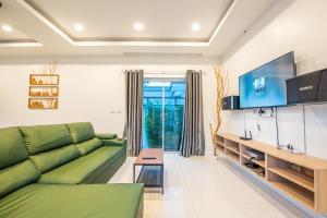 Una sala de estar con un sofá verde y un televisor. en Garden House Na Jomtien, en Na Jomtien