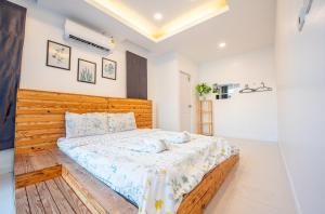 Un dormitorio con una cama grande con cabecero de madera. en Garden House Na Jomtien, en Na Jomtien