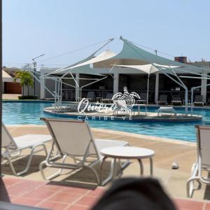 a swimming pool with chairs and an umbrella at Tucacas Casa del Mar Caribe in Tucacas