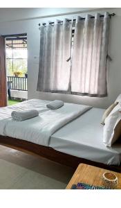 a large bed with white sheets and a window at 1RK charming apartment-1 in Assagao