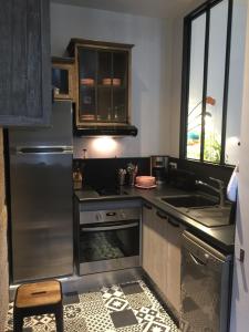 a kitchen with a stainless steel refrigerator and a sink at L'Annexe Apparthôtel du 11 D, 3 étoiles in Besançon