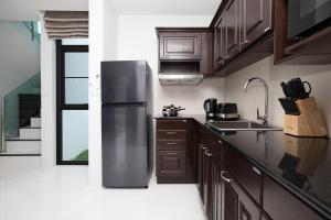 カマラビーチにあるNamara The Residences Aのキッチン(ステンレス製の冷蔵庫、木製キャビネット付)