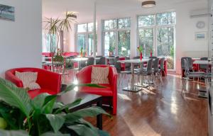a restaurant with red chairs and tables and windows at Hotel Lüneburg Süd in Melbeck