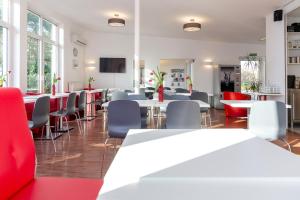 a restaurant with white tables and chairs and red chairs at Hotel Lüneburg Süd in Melbeck