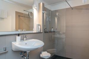 a bathroom with a sink and a shower at Hotel Lüneburg Süd in Melbeck
