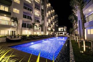 a swimming pool in front of a building at night at Mantra Condo M168 in Ban Phlong Sawai