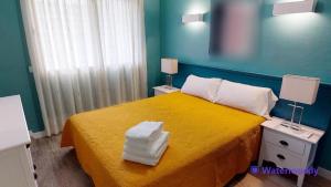 a bedroom with a yellow bed with towels on it at Apartamentos Eldorado in Lloret de Mar