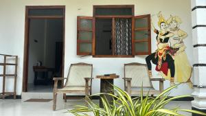 een muurschildering aan de zijkant van een huis met twee stoelen bij Ubay Guest House in Trincomalee +41 foto's