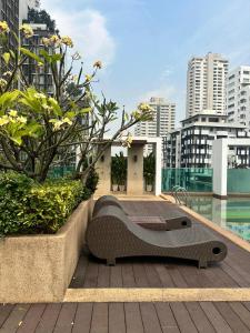 a bench sitting on a deck next to a pool at Spacious Sukhumvit Condo near EmQuartier in Bangkok