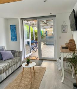 a living room with a couch and a table at Seatribe Cabin, Cozy snug by the Sea in South Hayling