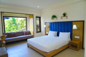 a bedroom with a large white bed and a window at Purple Cloud Hotel in Devanhalli
